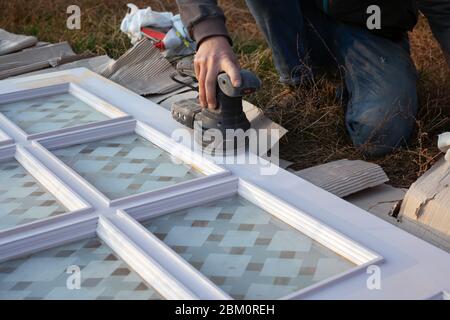restauration de vieilles portes en bois, nettoyage de surface avec un outil de meulage, préparation pour la peinture. Banque D'Images