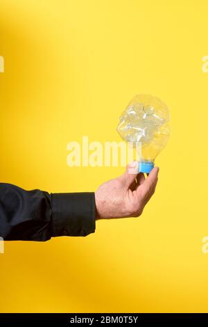 homme tenant une bouteille en plastique froissés sur fond jaune Banque D'Images
