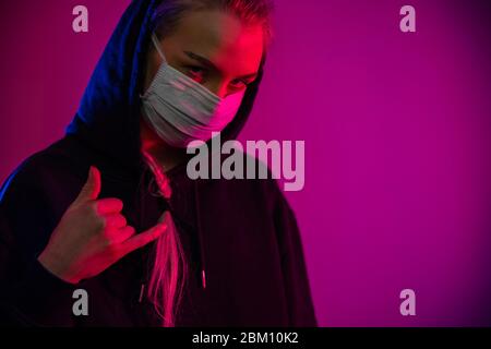 Femme épuisée ou déprimée dans un masque de protection avec des lumières multicolores Banque D'Images