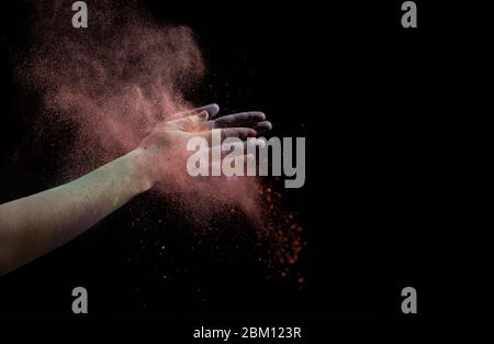 Clapez les mains pendant l'Holi. Nuage rouge de peinture sèche Banque D'Images