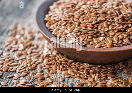 Les graines de lin se trouvent sur les vieux planches et dans une cuillère sur une table en bois. Le lin est utilisé pour prévenir les maladies cardiaques et être en surpoids. Banque D'Images