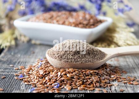 Graines de lin écrasées dans une cuillère en bois sur une pile de lin. Les graines de terre sont utilisées pour prévenir les maladies cardiaques et être en surpoids. Banque D'Images