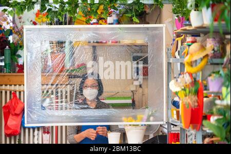 Dresde, Allemagne. 06e mai 2020. Une vendeuse de fleurs se trouve dans le hall du marché de Neustadt, dans son magasin, derrière un bouclier de sphite et porte un protège-bouche. Crédit : Robert Michael/dpa-Zentralbild/dpa/Alay Live News Banque D'Images