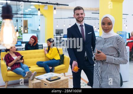Portrait d'un jeune homme d'affaires caucasien barbu habillé élégant décontracté et une femme hijab africaine posant dans un espace de travail de collègue moderne. Banque D'Images