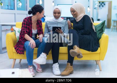 Groupe diversifié de jeunes femmes d'affaires multiethniques travaillant en équipe. Deux hijab musulmans et une collègue américaine discutant de questions importantes si Banque D'Images