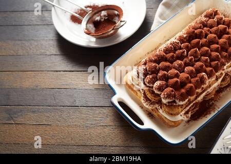 Délicieux dessert italien tiramisu avec fromage marscapuone et biscuits de boudoir parsemés de cacao servis sur une table avec espace copie Banque D'Images