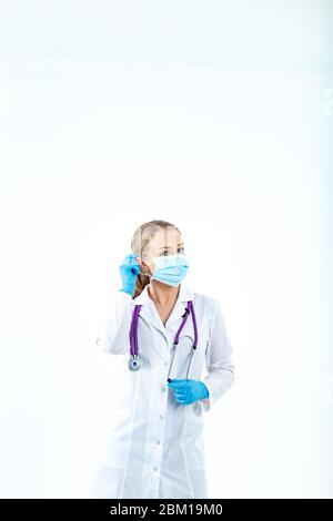 le médecin infirmière met un masque de protection. Une infirmière dans un masque respiratoire. Mettre des masques. Portez des gants. Beau docteur blond montre comment mettre sur un protec Banque D'Images