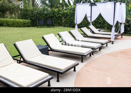 Vue tranquille sur la rangée de chaises longues blanches autour de la piscine de l'hôtel, personne en été. Banque D'Images