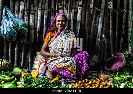 Une vieille femme souriante qui vend des légumes Banque D'Images