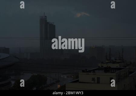 gratte-ciels à peine visibles, rue avec voitures, maisons pendant une tempête et de fortes pluies dans la ville Banque D'Images