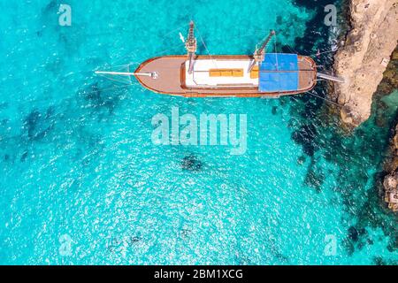 Bateau de plaisir en bois avec mât en bleu clair de mer. Vue aérienne. Banque D'Images