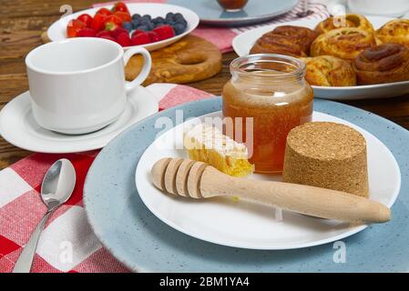 petit déjeuner au village, petits pains frais, café, baies et miel, sur une ancienne table en bois marron. Banque D'Images