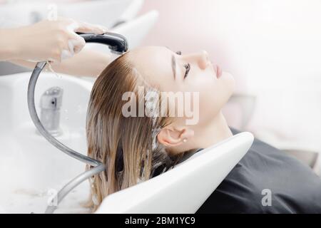 Belle blonde woman getting lavage des cheveux au salon de beauté. Soins traitement tête Concept Banque D'Images