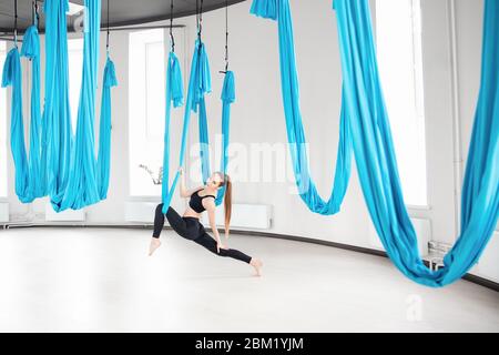 Jeunes femmes belles pratiquant le yoga aérien s'étirant dans la salle de gym Banque D'Images