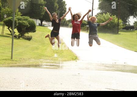 Jeunes filles jouant dans une grande flaque de sol après une forte pluie Banque D'Images