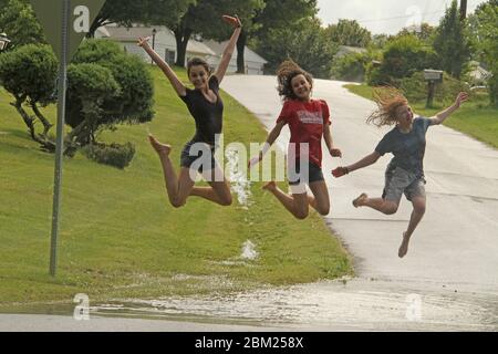 Jeunes filles jouant dans une grande flaque de sol après une forte pluie Banque D'Images