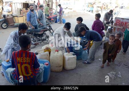 Les citoyens remplissent leurs bidons d'eau du robinet de la mosquée alors qu'ils sont confrontés à une pénurie d'eau potable dans leur région lors d'un confinement complet imposé par le gouvernement provincial en raison de l'augmentation du nombre de cas de coronavirus comme mesure préventive contre la propagation du coronavirus (COVID-19), Dans la région de Korangi à Karachi le mercredi 6 mai 2020. Banque D'Images