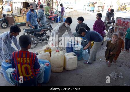 Les citoyens remplissent leurs bidons d'eau du robinet de la mosquée alors qu'ils sont confrontés à une pénurie d'eau potable dans leur région lors d'un confinement complet imposé par le gouvernement provincial en raison de l'augmentation du nombre de cas de coronavirus comme mesure préventive contre la propagation du coronavirus (COVID-19), Dans la région de Korangi à Karachi le mercredi 6 mai 2020. Banque D'Images