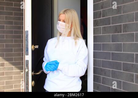 Une jeune fille est debout sur le porche de sa maison dans un masque respiratoire. Banque D'Images