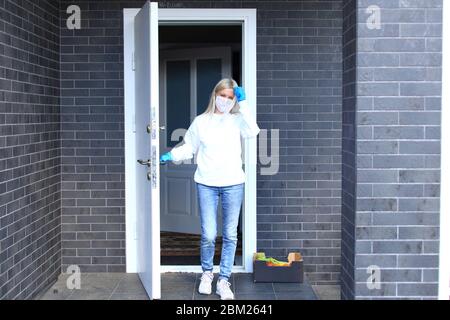 Une jeune fille est debout sur le porche de sa maison dans un masque respiratoire. Banque D'Images