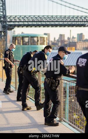 New York, États-Unis - Mai 5 2020 : des policiers dans des groupes à Domino Park supervisent les gens et les foules pour les social distancer portant des uniformes et des masques Ove Banque D'Images