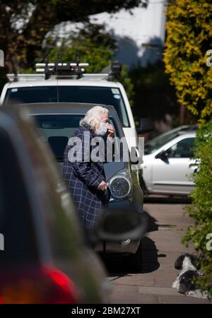 Une femme âgée portait un équipement de protection individuelle et tourait son masque, pendant la pandémie COVID-19 de 2020. Balham, Londres, Royaume-Uni Banque D'Images