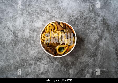 Emporter la soupe au nouilles udon japonais de style asiatique avec bœuf, champignons et légumes dans un emballage/récipient en plastique. Restauration rapide traditionnelle. Prêt t Banque D'Images