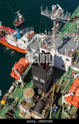 Vue de dessus de l'orange, rouge et blanc Nikolaos V remorqueurs et fûts de pétrole, bateaux de sauvetage sur le pont de réservoir de fioul, port du Pirée, Athènes, Grèce Banque D'Images