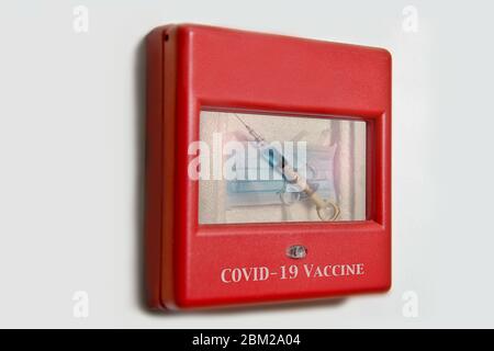 Image concept d'une seringue et d'un masque facial contenus dans une alarme murale d'urgence à utiliser avec les problèmes de Covid-19 et de coronavirus. Banque D'Images