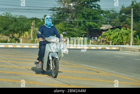 Un homme sur une moto portant un masque facial. Banque D'Images