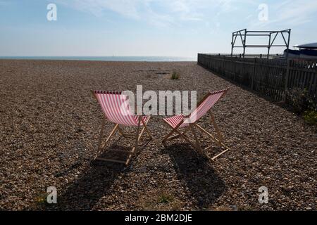 Deux chaises longues rayées rouges et blanches sur la plage de galets à Walmer, près de Deal, Kent, Royaume-Uni Banque D'Images