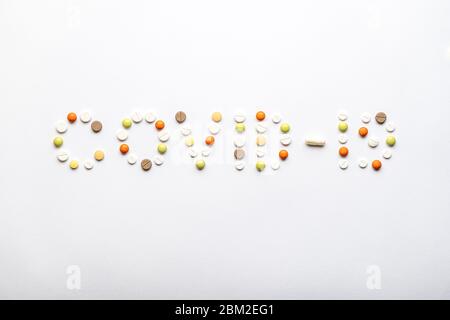 inscription covid-19 avec pilules et capsules plates sur un fond blanc espace de copie. Coronavirus, médecine et santé, concept de sécurité. Banque D'Images