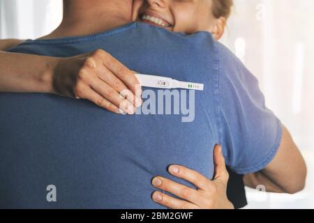 couple heureux se hembrassant après un test de grossesse positif Banque D'Images