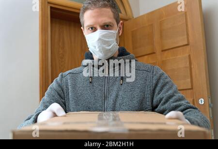 Le coursier en masque médical et gants livre le colis. Service de livraison de colis. Banque D'Images