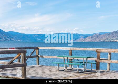 Table de pique-nique sur la jetée de Naramata avec vue panoramique sur le lac Okanagan et les montagnes Banque D'Images