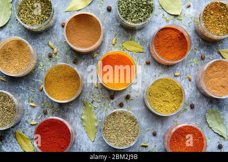 Variété d'herbes séchées colorées et d'épices dans des tasses. Sélection d'herbes et d'épices sur fond gris. Cuisine, manger concept. Vue de dessus. Banque D'Images