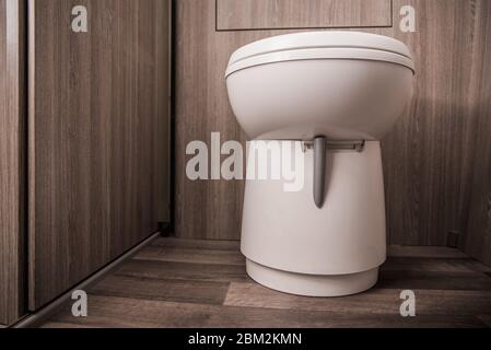 Gros plan des toilettes blanches dans Tan petit espace de la cabine de toilettes pour véhicule de plaisance. Banque D'Images
