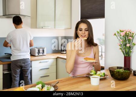 Un jeune couple marié prenant le petit déjeuner à la maison. Un mari prépare le petit déjeuner pour sa femme bien-aimée. Banque D'Images