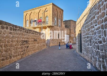 Les enfants jouent dans de vieilles rues étroites près des maisons traditionnelles en pierre de Midyat, Mardin, Turquie Banque D'Images