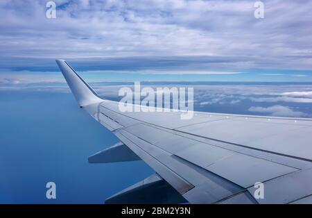 Vue aérienne de la fenêtre d'avion au-dessus des nuages sous ciel bleu. Vue depuis la fenêtre de l'avion. Compagnie aérienne, entreprise Banque D'Images