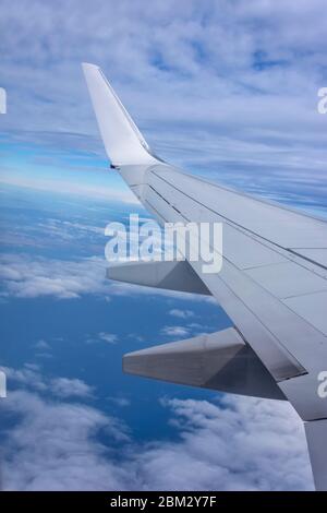 Vue aérienne de l'avion volant au-dessus de nuages et de ciel ombragés. L'aile d'avion survole l'île tropicale. Vue depuis la fenêtre de l'avion de la durée du moment émotionnel Banque D'Images