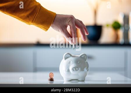 Finances personnelles, femme mettant l'argent dans une banque de piggy -- richesse et concept financier. Banc de porc blanc au premier plan. Banque D'Images