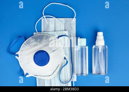 Masque filtrant N95, masques chirurgicaux jetables, flacons de désinfectant antibactérien pour les mains (gel antiseptique pour alcool) sur fond bleu, à Banque D'Images