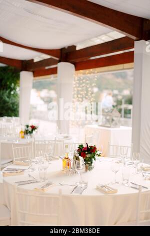 Réception de table de mariage. Tables rondes avec nappes blanches et chaises Chiavary blanches sous une grande tente blanche, sur fond d'un Banque D'Images