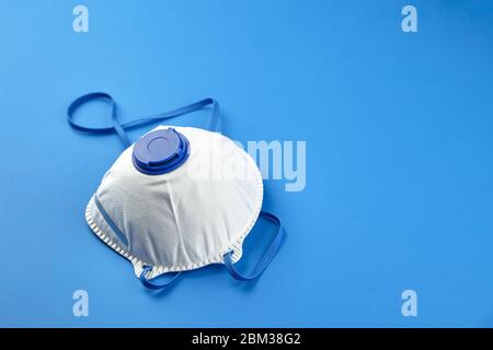 Respirateur FFP2, protection contre la pandémie de coronovirus COVID-19. Masque filtrant blanc sur fond bleu avec espace de copie. N95 respon Banque D'Images