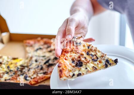 Tranche de pizza avec champignons, fromage et jambon dans la main mâle Banque D'Images