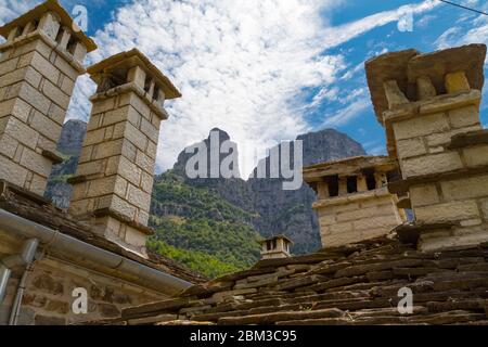 Vue sur les tours d'Astraka (montagne Tymfi) à Mikro Papigo, Grèce. Cheminées et toits en pierres au premier plan et tours en arrière-plan. Banque D'Images