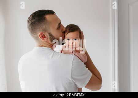 Young Caucasian father carrying barbu bébé nouveau-né sur l'épaule. Mâle homme portefeuille mère enfant fille fils dans les bras. Documentaire de vie authentique Banque D'Images