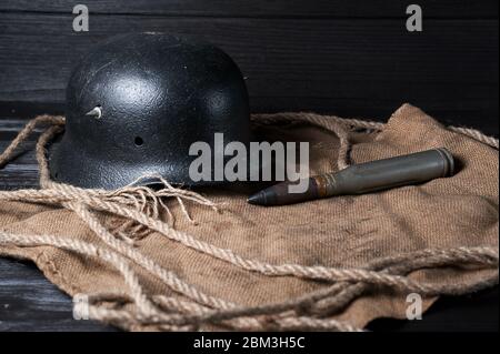 Casque allemand encore vivant et cartouche lourde sur fond noir et toile de jute Banque D'Images