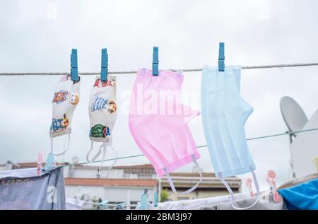 Jeu de masques lavables suspendus sur une ligne de linge. L'ensemble représente la famille contre le covid-19 Banque D'Images